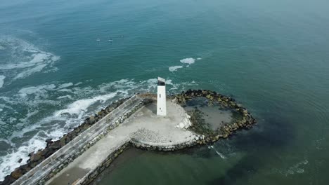 pequeño faro blanco en el borde del muelle rocoso