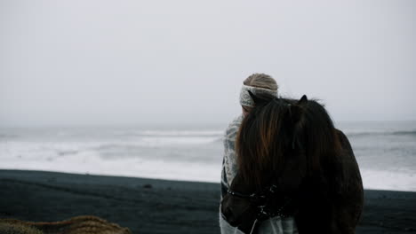 woman and horse at icelandic black sand beach