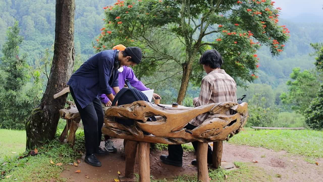 Young students connect and share ideas outdoors at unique wooden table