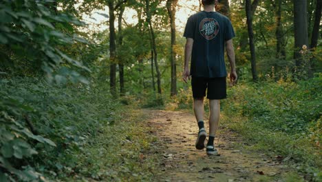 young male walking through woods in the evening