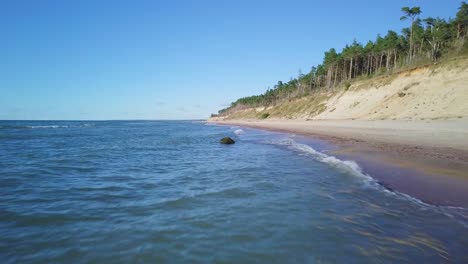 Luftaufnahme-Des-Ostseestrandes-In-Jurkalne-An-Einem-Sonnigen-Tag,-Weiße-Sandklippe-Beschädigt-Durch-Wellen,-Küstenerosion,-Klimaveränderungen,-Weitwinkel-drohnenaufnahme,-Die-Sich-Tief-Vorwärts-Bewegt-1