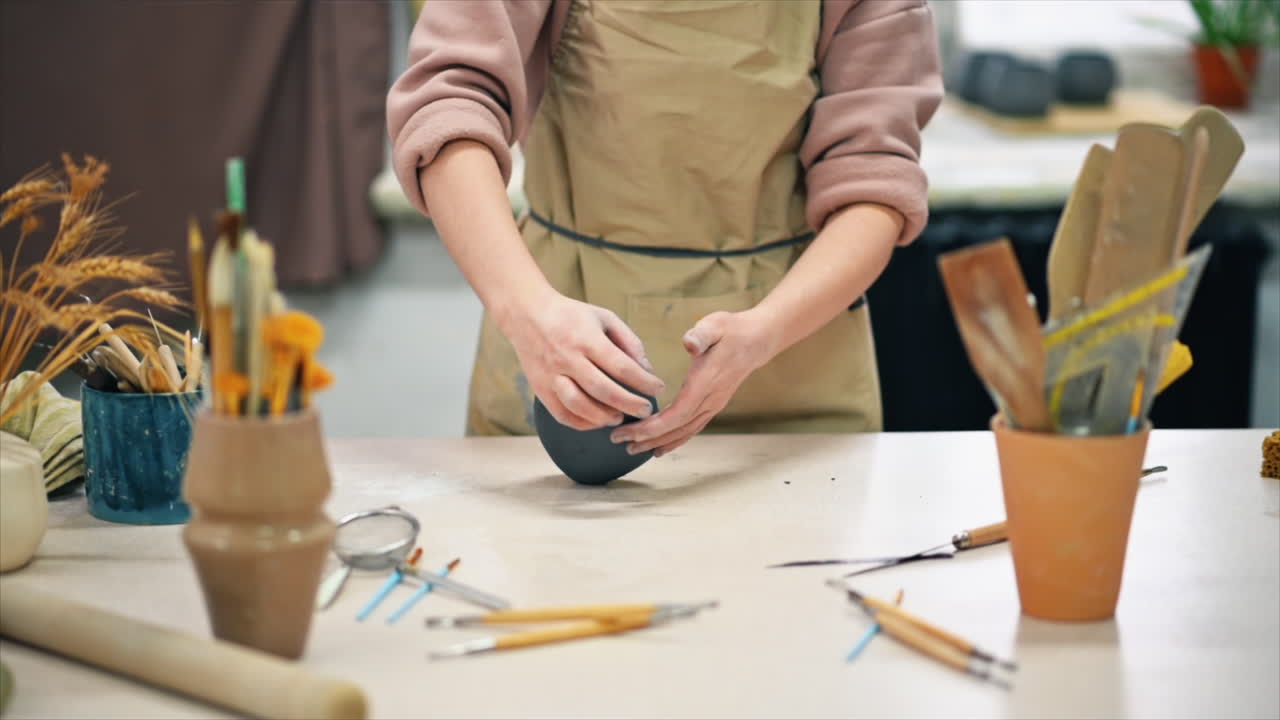 The master of sculpting pottery working in a studio. Kneading a piece of clay with her hands. Tools on the table. Slow motion