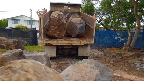 un camión que entrega una carga de grandes rocas a un sitio de construcción