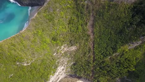 Increíble-Vista-Aérea-Vuelo-Inclinado-Hacia-Abajo-Vuelo-De-Drones-Borde-Acantilado-Hasta-La-Playa-Mágica-De-Grandes-Olas-Intactas-Nusa-Penida-En-Bali-Indonesia-Es-Como-Un-Parque-Jurásico