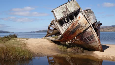 tiro basculante de un barco point reyes podrido y naufragado varado en una soleada costa de la bahía de tomales