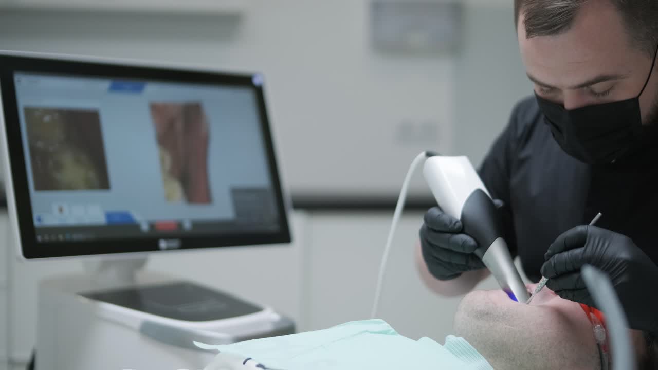 el médico escanea los dientes del paciente en la clínica. el dentista sostiene en su mano un escáner 3d manual para la mandíbula y la boca. salud dental. crea un modelo 3d de dientes y encías en un monitor médico.