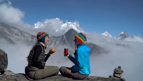 two girls are drinking tea in the mountains