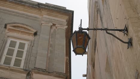 antique street lamp on exterior wall of a building in mdina, malta