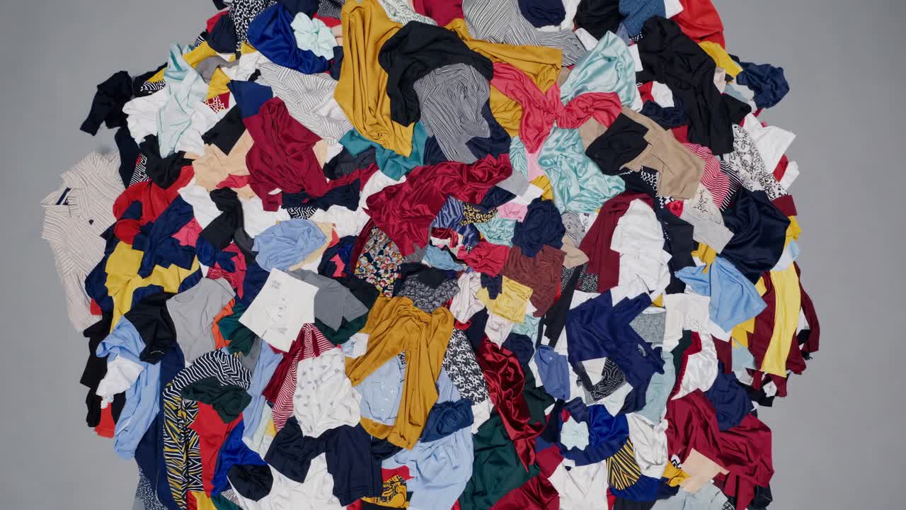 Top-down view of a colorful pile of clothes on a gray background, showcasing a vibrant mix