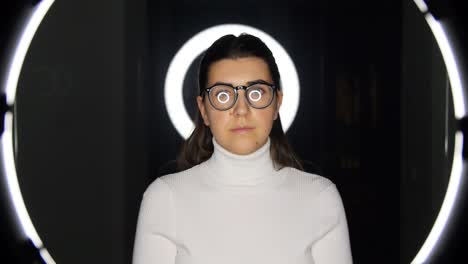 woman in glasses over white illumination on black