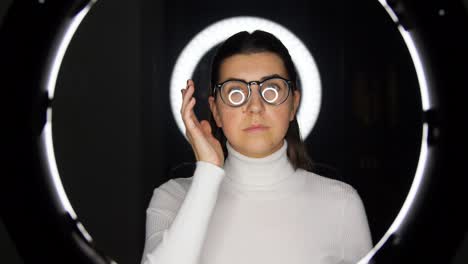 woman in glasses over white illumination on black