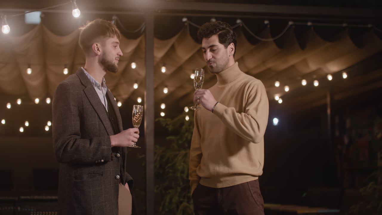 새해 전야 파티에서 서로 이야기하고 샴페인을 마시는 두 명의 우아한 남자