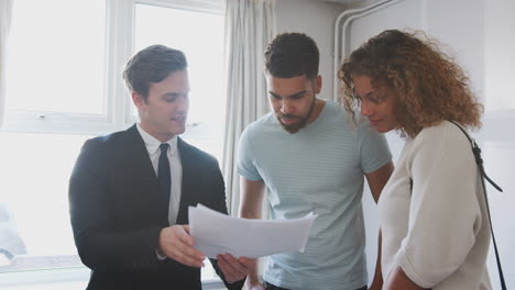 couple buying house for the first time looking at survey with realtor