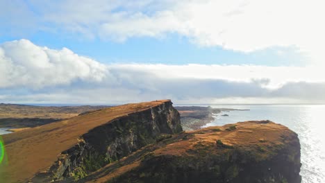 Vista-Aérea-De-Drones-Volando-Sobre-Hermosos-Acantilados-Junto-Al-Océano-Con-Un-Viajero-Parado-Cerca-Del-Borde-De-Un-Acantilado