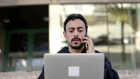 hombre enfocado usando portátil y teléfono inteligente