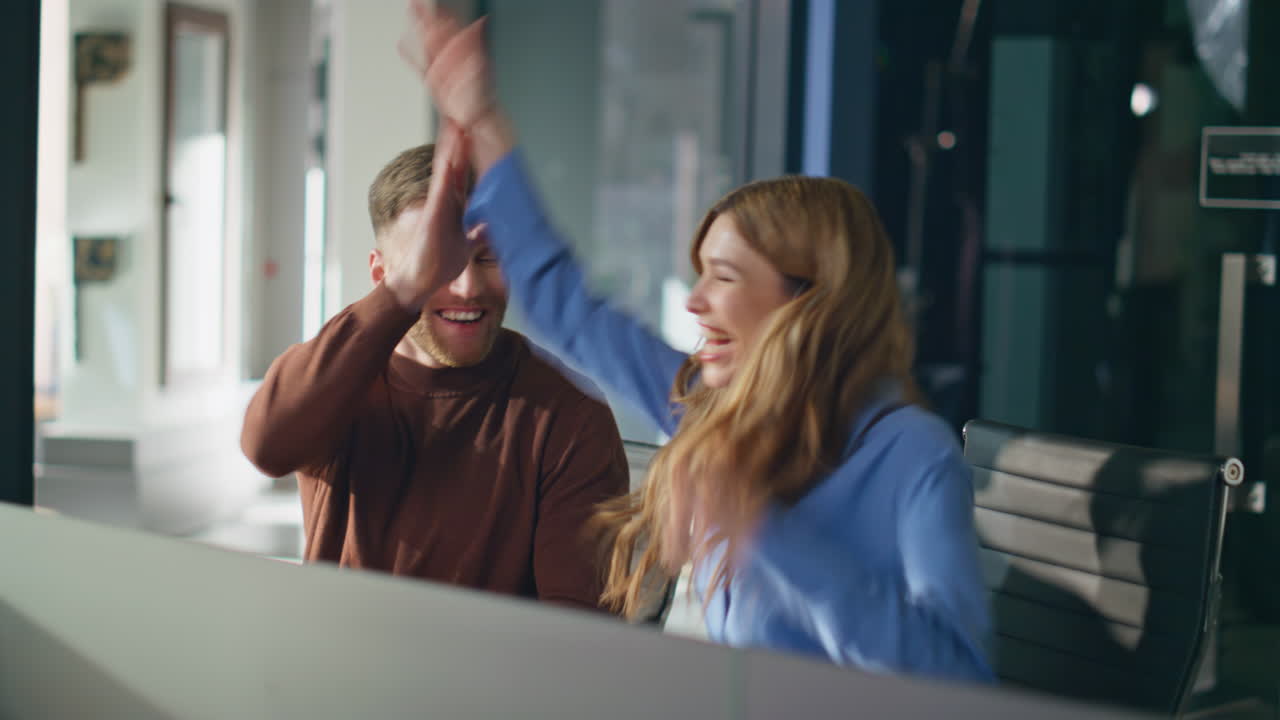 Two colleagues giving five rejoicing project success at office workplace closeup