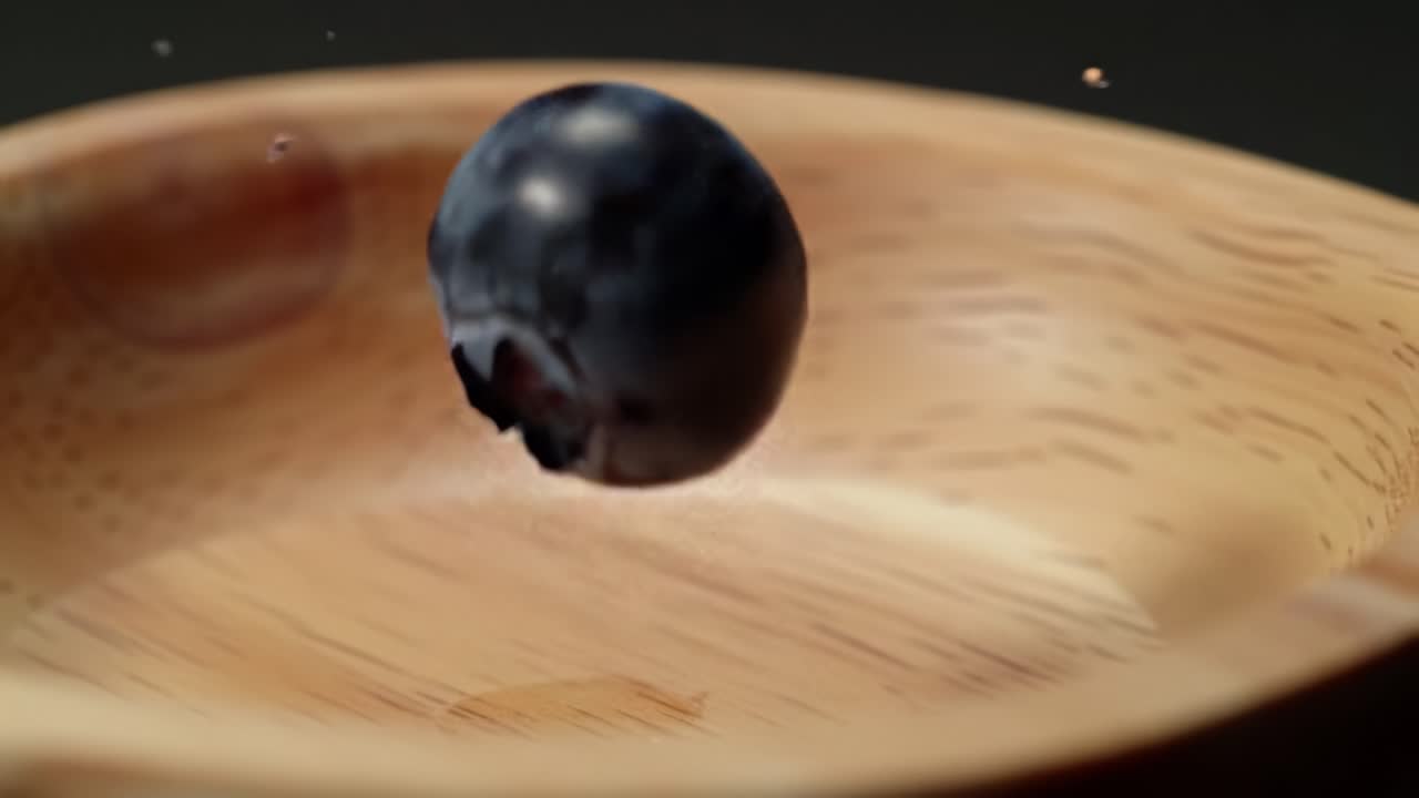 A Close-Up Exploration of a Fresh Blueberry as It Falls Gracefully into a Wooden Bowl, Capturing the Essence of Natural Ingredients in Culinary Arts