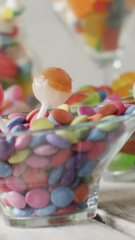 video of colourful various sweets in glass vessels on wooden table