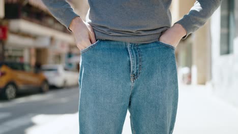 young hispanic man showing empty pockets at street