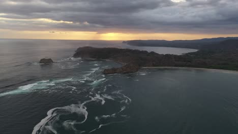 Vorágine-De-Agua-Formándose-En-La-Costa-De-Costa-Rica-En-El-Océano-Pacífico-Al-Atardecer-Con-Península-Rocosa,-Tiro-Aéreo