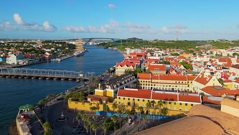 golden hour light spread across willemstad vibrant colored buildings with ship docked in port