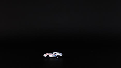 a toy car moves steadily across a dark background