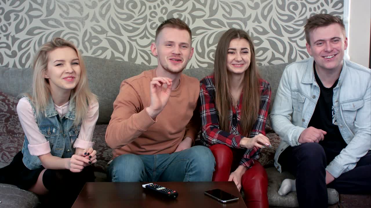 젊은 친구들의 행복하고 캐주얼한 그룹, 집에서 함께 어울리고, 텔레비전을 통해 음악을 듣고