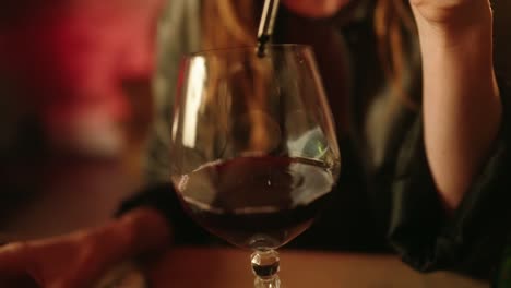 Woman-putting-poisson-into-red-wine-glass-with-pipette