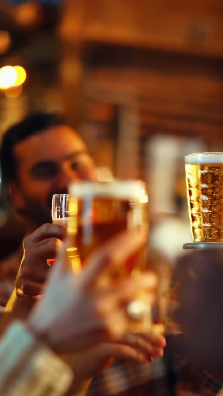 Video ravvicinato di amici che brindano con bicchieri di birra, catturando un'atmosfera vivace e festosa