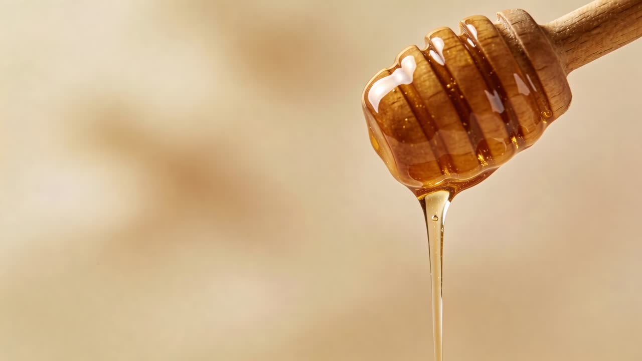 Mestolo di legno che gocciola rilasciando miele per gravità, formando un flusso di goccioline in studio, con spazio per il testo.