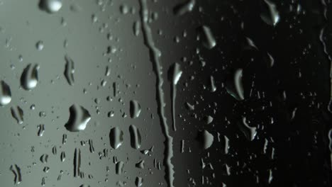 rain water droplets falling down on window glass, reflecting liquid shapes, macro shot