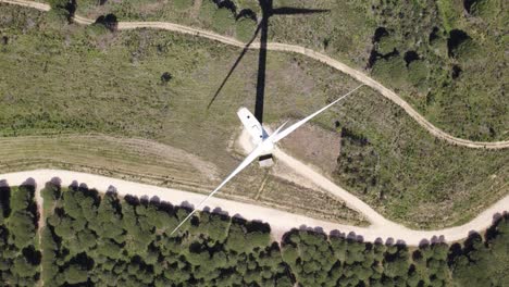 aerial top down view, spinning wind turbine on a green field, drone orbit