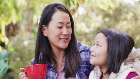 video of happy asian mother and daughter embracing and talking in garden