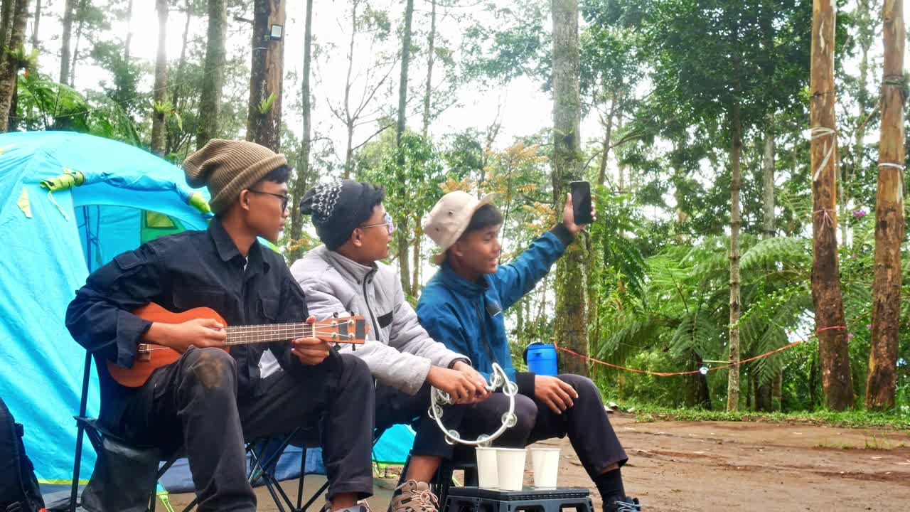 Camping friends taking selfies while enjoying music and creating memories in nature