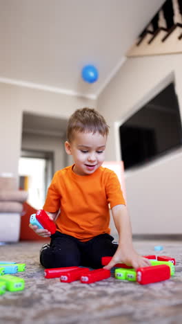 lovely smiling toddler picks colorful bricks from the floor. happy child playing at home. vertical video.