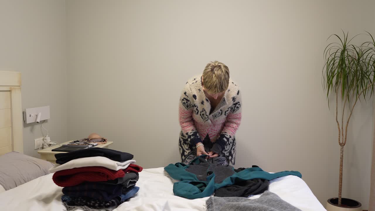 Woman folding clothes in bedroom