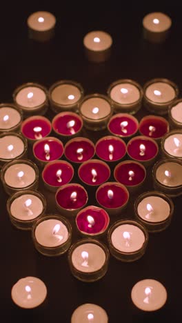 Vertical-Video-Of-Romantic-Red-And-White-Candles-In-the-Shape-Of-A-Heart-On-Black-Background-2