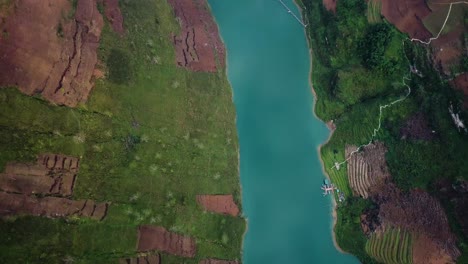 an ascending drone shot of a calm turquoise river reveals a reservoir