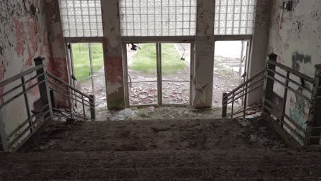 slider footage from the top of the stairway in an abandoned high school front entrance