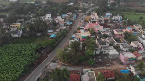 aerial view over an indian village with colorful houses in a natural green landscape, tilt-down shot, travel concept