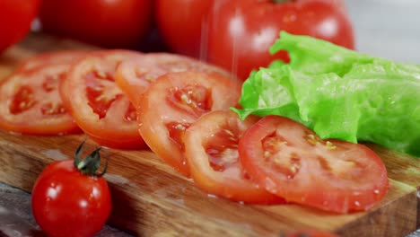 on slices tomato on cutting board falling drops of water.