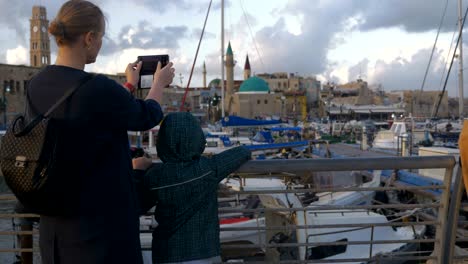 una mujer con su hijo tomando fotos cuando visitan el puerto de acre, israel