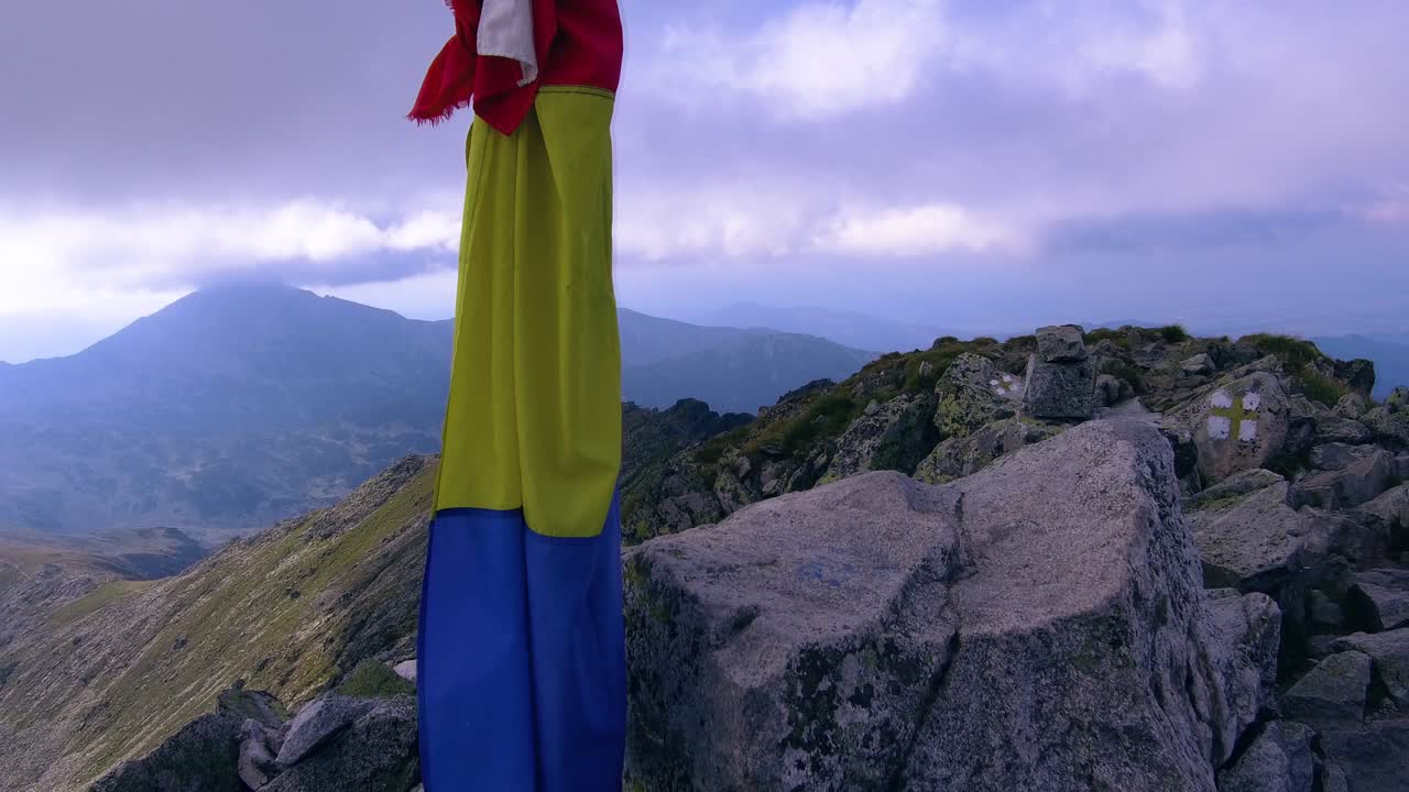 bandera rumana en la cima de la montaña atada a un poste con cámara panorámica a la derecha