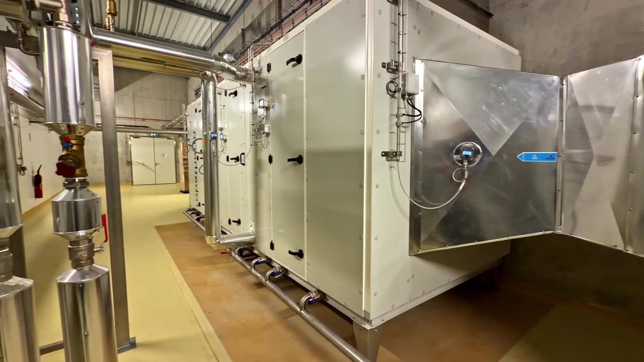 Brightly lit industrial facility showcasing stainless steel ductwork and ventilation system. Ideal for use in engineering or industrial design content.