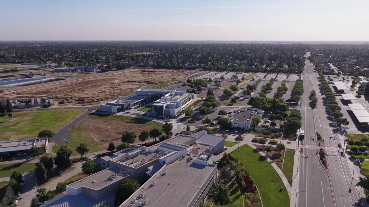 Sunny day aerial view of the Clovis Community College campus buildings, parking lots, and surrounding cityscape in Fresno, California, showcasing the modern architecture and green spaces