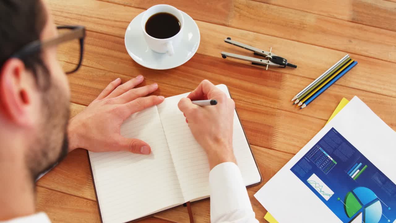 책상 에 앉아 일기 를 쓰는 사업가