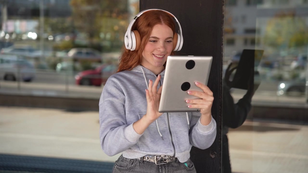 Una giovane donna si gode un momento di relax all'aperto, con le cuffie e sorridendo.