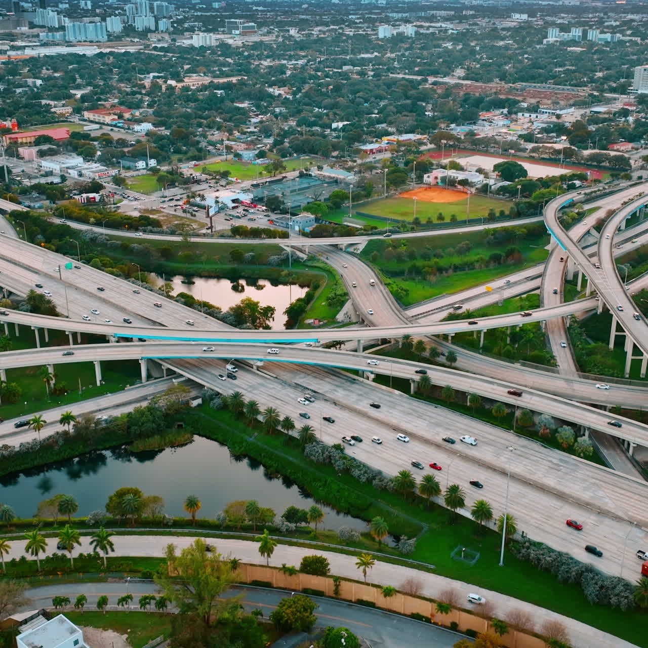 Road interchange of highways and freeways in colorful Miami. City scenery with lively traffic from top view.