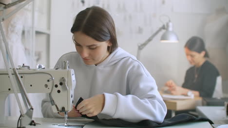 costura de ropa. costureras en el trabajo en el taller cosiendo ropa en la máquina de coser. modistas cosen ropa en el atelier. dos mujeres costureras. costura en el negocio de cosida.