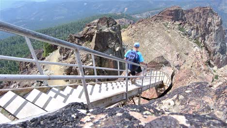 a hiker climbing down the steep stairs from the sierra buttes fire tower in tahoe national forest california